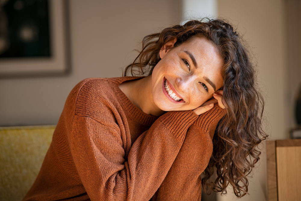 Image of a dentist smiling and pointing to a digital scan of a patient's mouth with dental implants, in front of the patient who is also smiling. No text on the image.