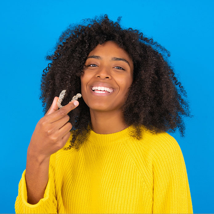 Woman in yellow sweater with Invisalign
